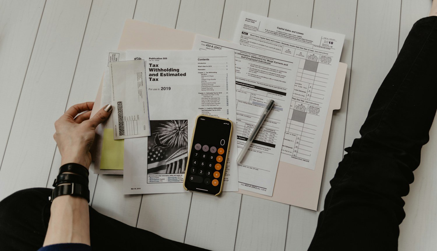 Persona organizando documentos y cuentas sobre una mesa de trabajo